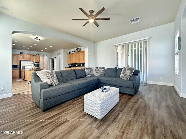 living area featuring arched walkways, baseboards, visible vents, and a healthy amount of sunlight