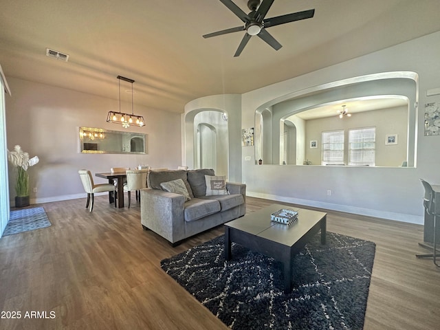 living area featuring baseboards, visible vents, arched walkways, and wood finished floors