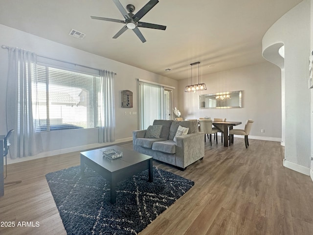 living area featuring a ceiling fan, wood finished floors, visible vents, and baseboards