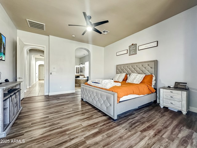 bedroom featuring visible vents, arched walkways, and wood finished floors