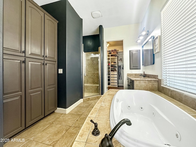 bathroom featuring a spacious closet, a stall shower, vanity, a whirlpool tub, and baseboards