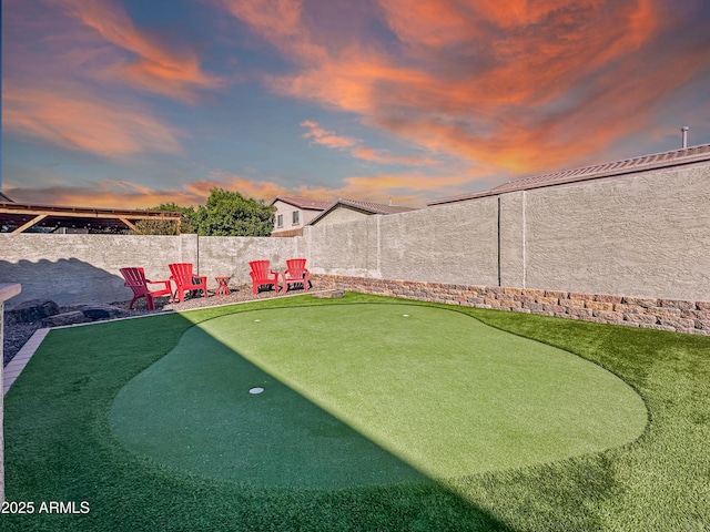 yard at dusk featuring a fenced backyard