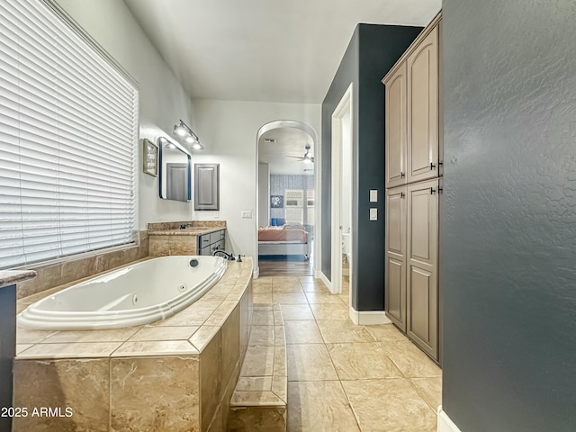 bathroom with a ceiling fan, a jetted tub, vanity, and ensuite bathroom