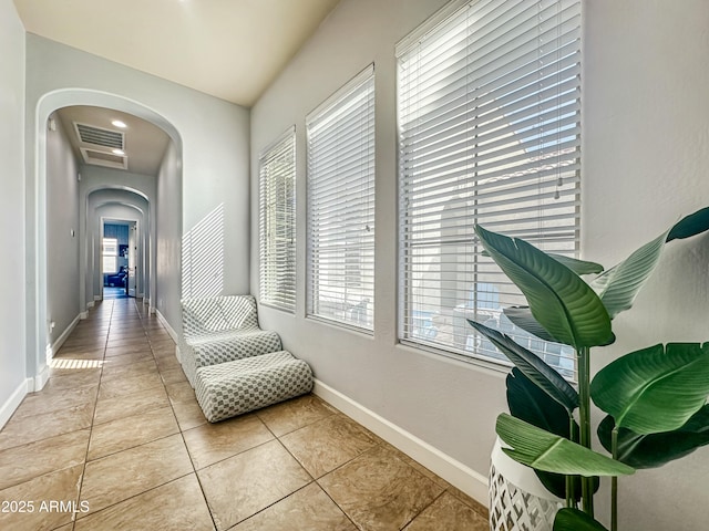 corridor featuring baseboards, visible vents, arched walkways, and tile patterned floors