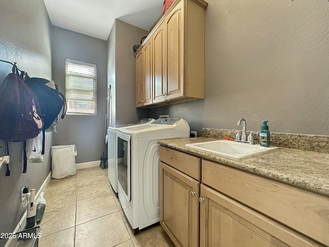 washroom with washer and clothes dryer, cabinet space, light tile patterned flooring, a sink, and baseboards