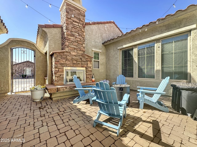 view of patio / terrace featuring a gate and an outdoor stone fireplace