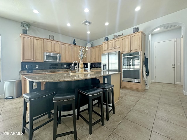 kitchen with arched walkways, visible vents, decorative backsplash, appliances with stainless steel finishes, and light brown cabinets