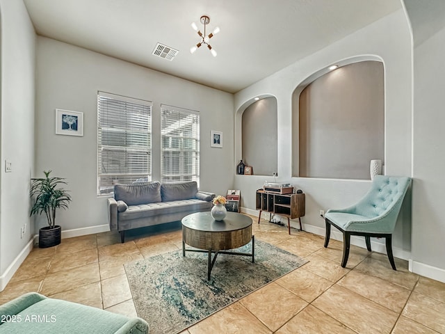 living area featuring tile patterned floors, visible vents, baseboards, and an inviting chandelier