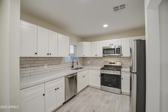 kitchen featuring stainless steel appliances, white cabinetry, and sink