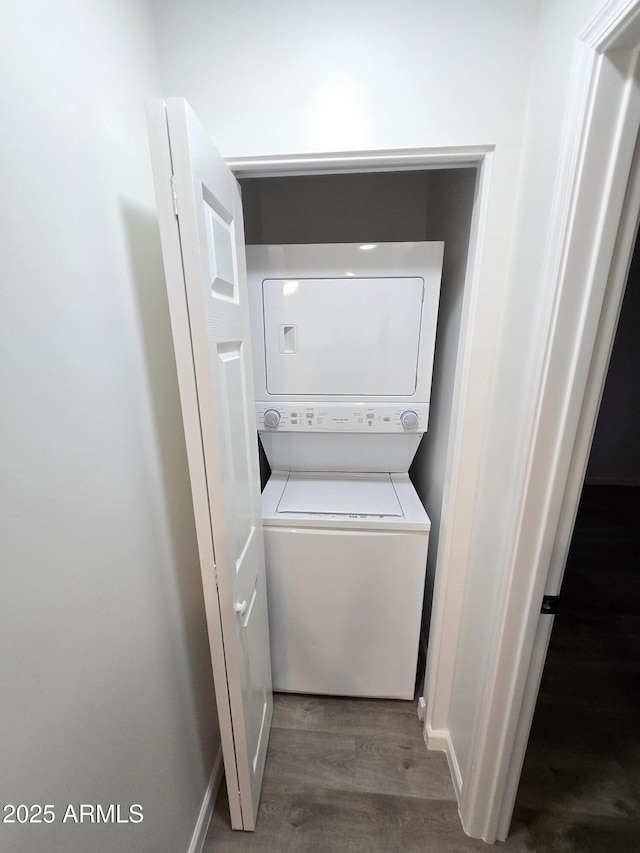 laundry room featuring dark wood-type flooring and stacked washing maching and dryer