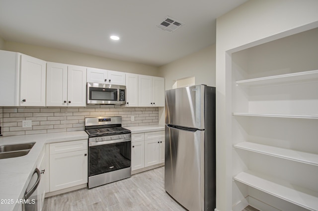 kitchen featuring white cabinetry, stainless steel appliances, sink, and light hardwood / wood-style floors