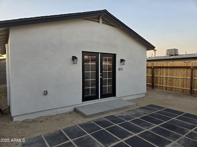 exterior entry at dusk featuring cooling unit and a patio