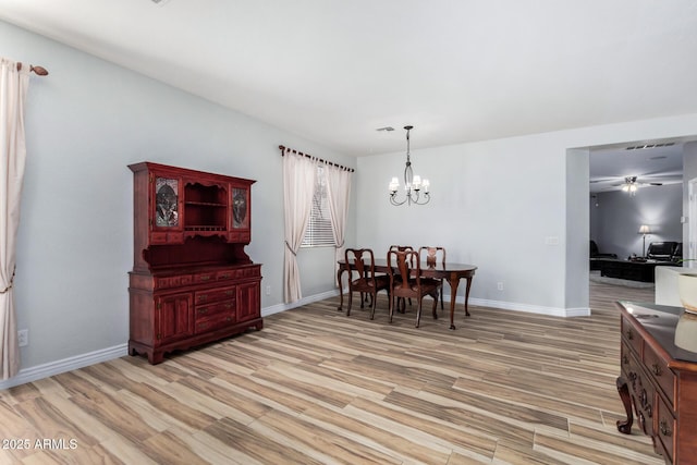 dining room with ceiling fan with notable chandelier and light hardwood / wood-style floors