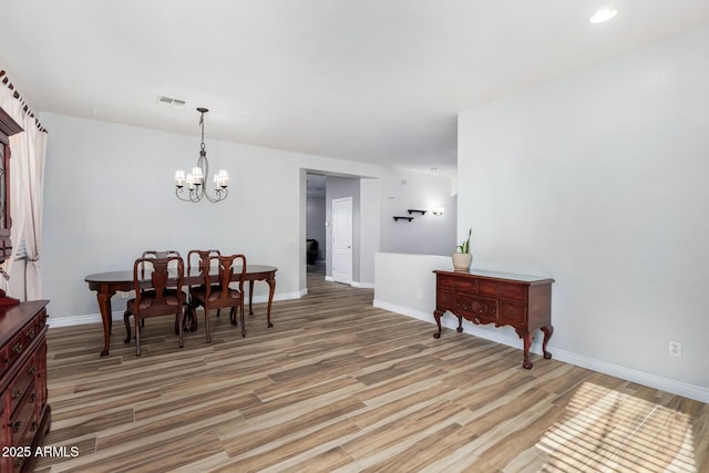 dining room with hardwood / wood-style floors and an inviting chandelier