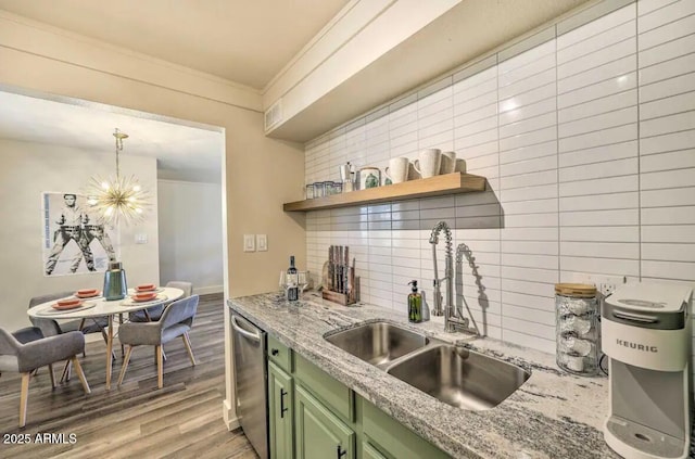 kitchen featuring a sink, light wood-style floors, green cabinets, stainless steel dishwasher, and decorative backsplash