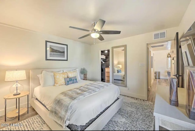 bedroom with wood finished floors, visible vents, baseboards, a ceiling fan, and a closet