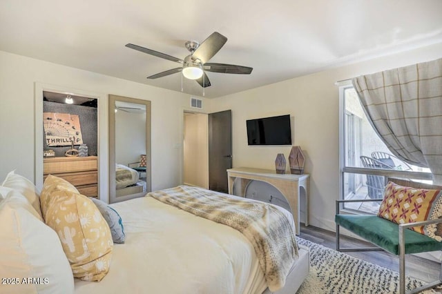 bedroom with ceiling fan, visible vents, and wood finished floors