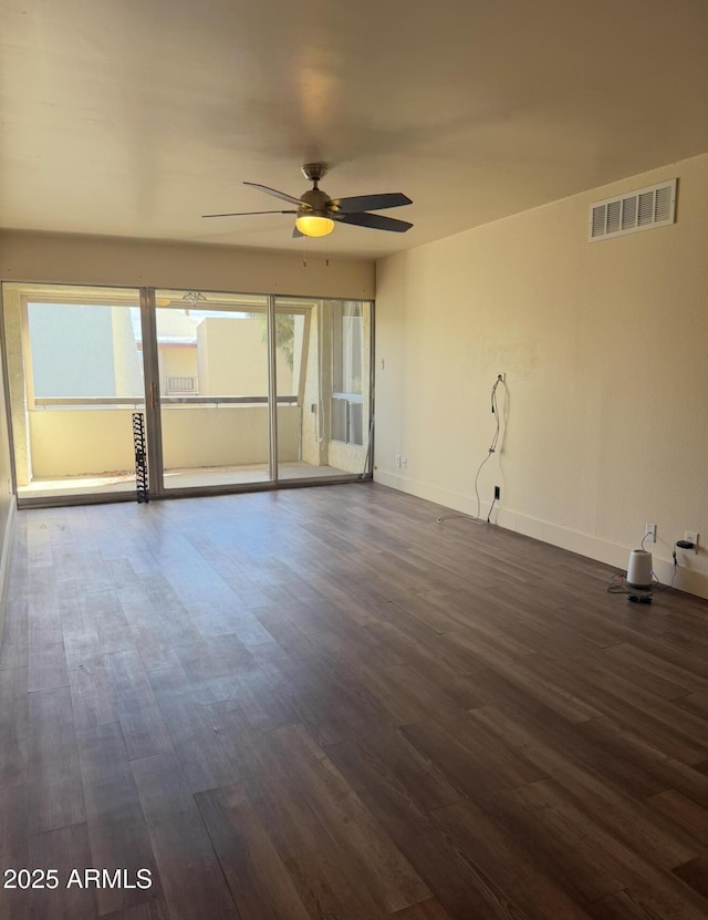 empty room featuring dark wood-style floors, visible vents, ceiling fan, and baseboards