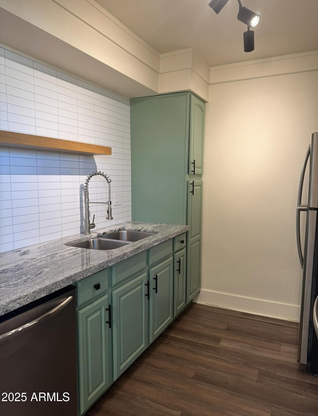 kitchen featuring dark wood-style flooring, a sink, green cabinets, appliances with stainless steel finishes, and tasteful backsplash