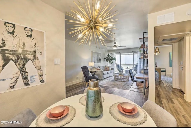 living area featuring baseboards, wood finished floors, visible vents, and an inviting chandelier