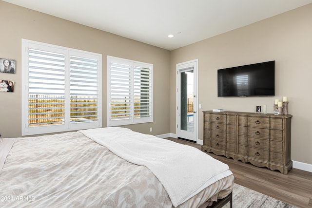 bedroom with access to outside, recessed lighting, wood finished floors, and baseboards