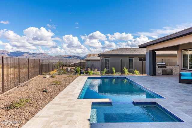 view of swimming pool featuring a patio, area for grilling, a fenced backyard, a pool with connected hot tub, and a mountain view