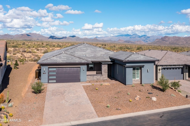 view of front of house with decorative driveway, an attached garage, a mountain view, and stucco siding