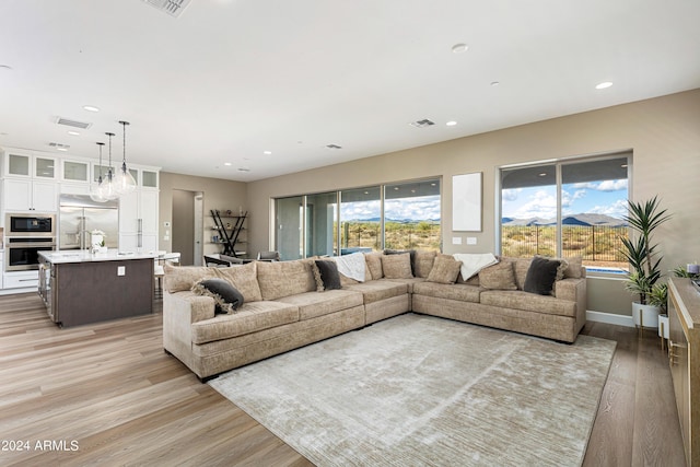 living area with light wood-style flooring, baseboards, and recessed lighting