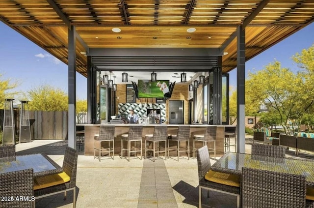 view of patio / terrace featuring fence, an outdoor bar, and outdoor dining space