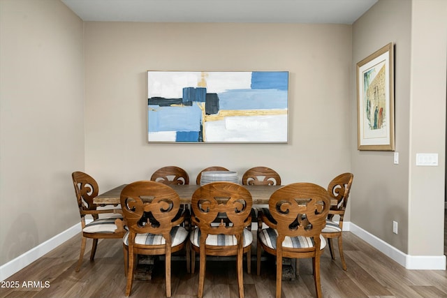 dining space with baseboards and wood finished floors