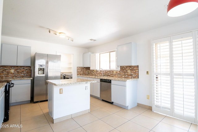 8055 W Sanna St, Peoria, AZ 85345 - kitchen featuring stainless steel appliances, decorative backsplash, a kitchen island, a sink, and light stone counters
