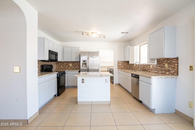 8055 W Sanna St, Peoria, AZ 85345 - kitchen featuring black appliances, a kitchen island, tasteful backsplash, and light stone counters