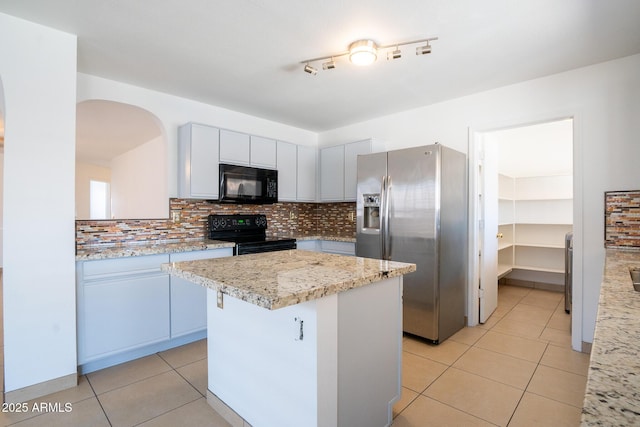 8055 W Sanna St, Peoria, AZ 85345 - kitchen featuring black appliances, light tile patterned floors, backsplash, a center island, and arched walkways