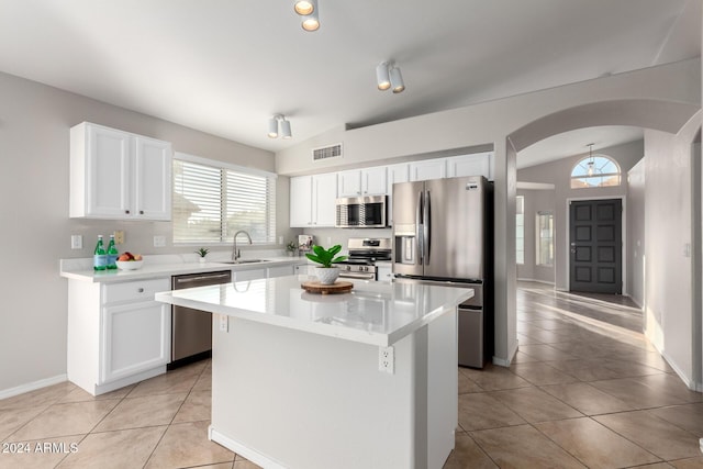 kitchen featuring white cabinets, appliances with stainless steel finishes, lofted ceiling, and a kitchen island