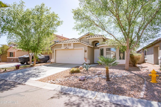 mediterranean / spanish house featuring a tile roof, stucco siding, an attached garage, and concrete driveway