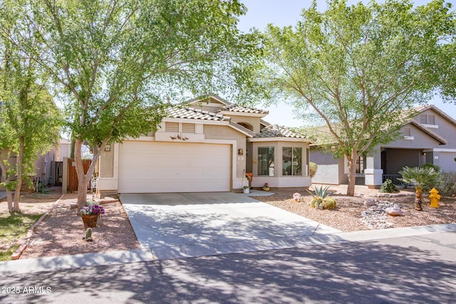 view of front of home featuring stucco siding, a garage, concrete driveway, and a tile roof