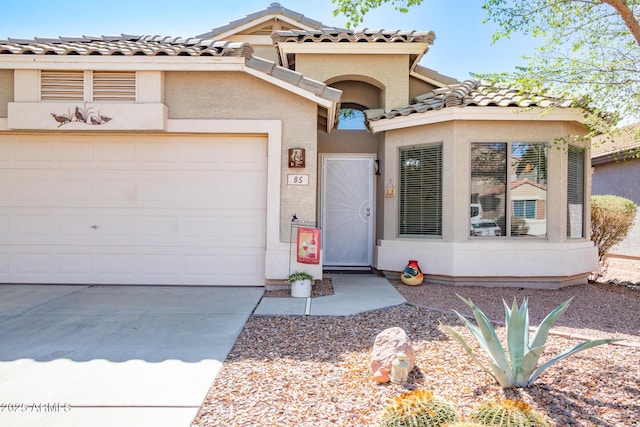 mediterranean / spanish house with stucco siding, a garage, concrete driveway, and a tiled roof