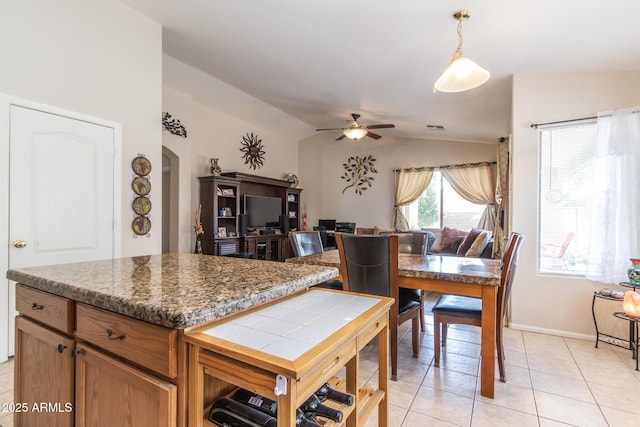 kitchen with light tile patterned floors, a ceiling fan, arched walkways, vaulted ceiling, and decorative light fixtures