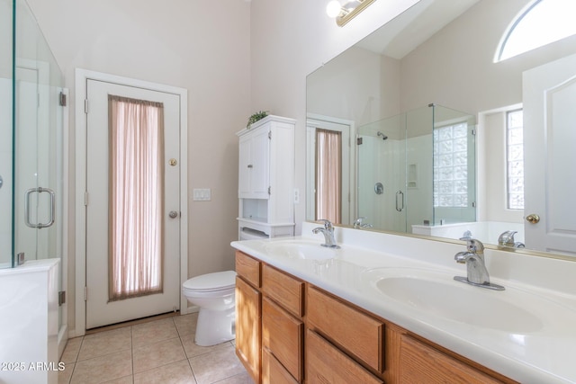 bathroom featuring tile patterned flooring, toilet, a stall shower, and a sink