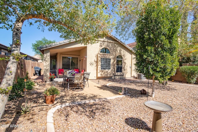 rear view of house with a tiled roof, a patio area, a fenced backyard, and stucco siding