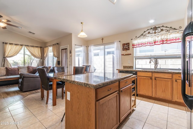 kitchen featuring visible vents, a sink, open floor plan, light tile patterned flooring, and vaulted ceiling