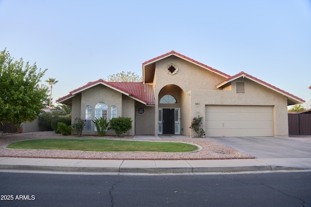 mediterranean / spanish house featuring a tiled roof, a garage, stucco siding, and a front yard