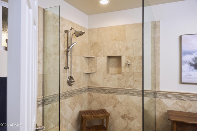 full bathroom featuring tiled shower and tile walls