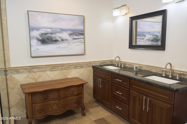 full bathroom featuring tile walls, a sink, and a wainscoted wall
