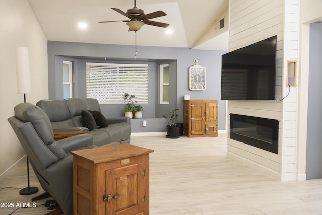 living area featuring a ceiling fan, visible vents, a glass covered fireplace, light wood finished floors, and baseboards