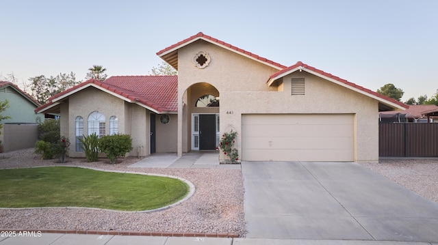 mediterranean / spanish-style home with a front yard, an attached garage, a tile roof, concrete driveway, and stucco siding