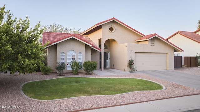 mediterranean / spanish house featuring a tiled roof, a garage, stucco siding, a front yard, and driveway