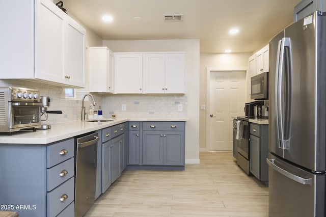 kitchen with a sink, visible vents, appliances with stainless steel finishes, and white cabinetry