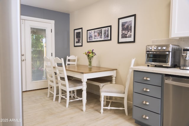 dining space with a toaster, light wood-style floors, and baseboards