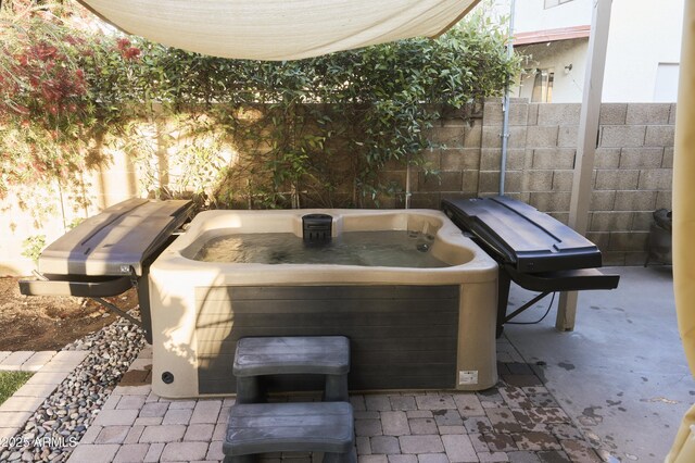 view of patio featuring fence and a hot tub